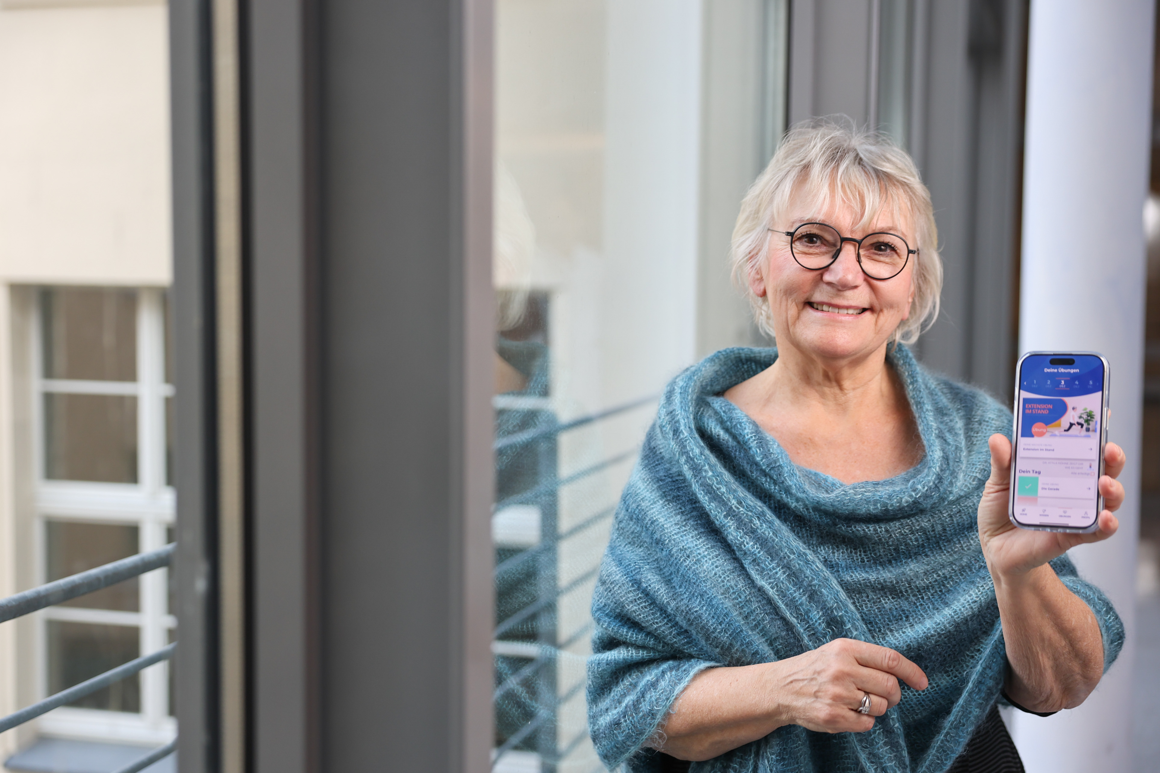 Seniorin zeigt die ActiveTEP-App auf ihrem Handy