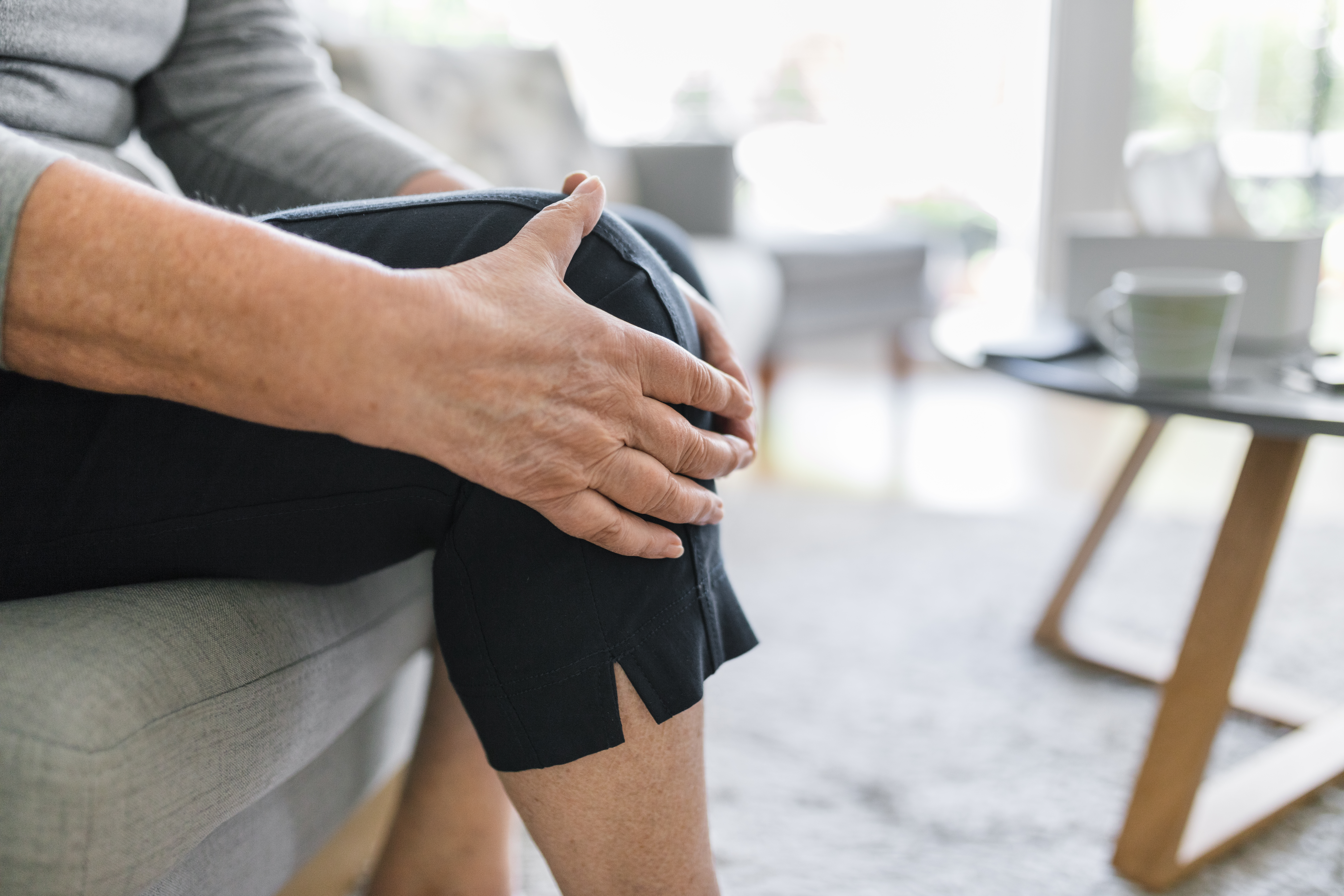 Frau hält sich zuhause das schmerzende Knie